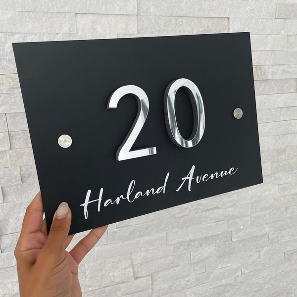 Black metal house number and street sign with elegant serif font