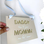 Acrylic page boy sign with white lettering and floral design for wedding ceremony.