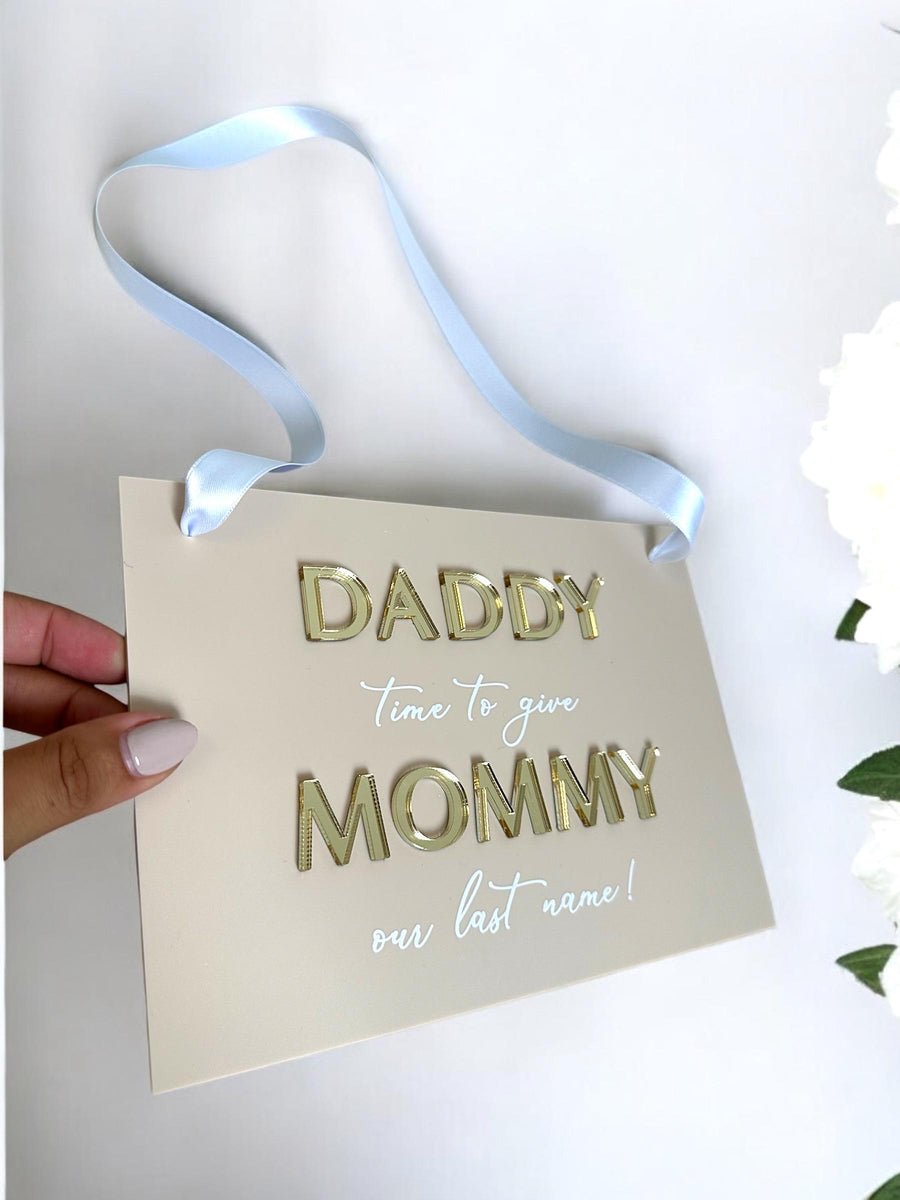 Acrylic page boy sign with white lettering and floral design for wedding ceremony.